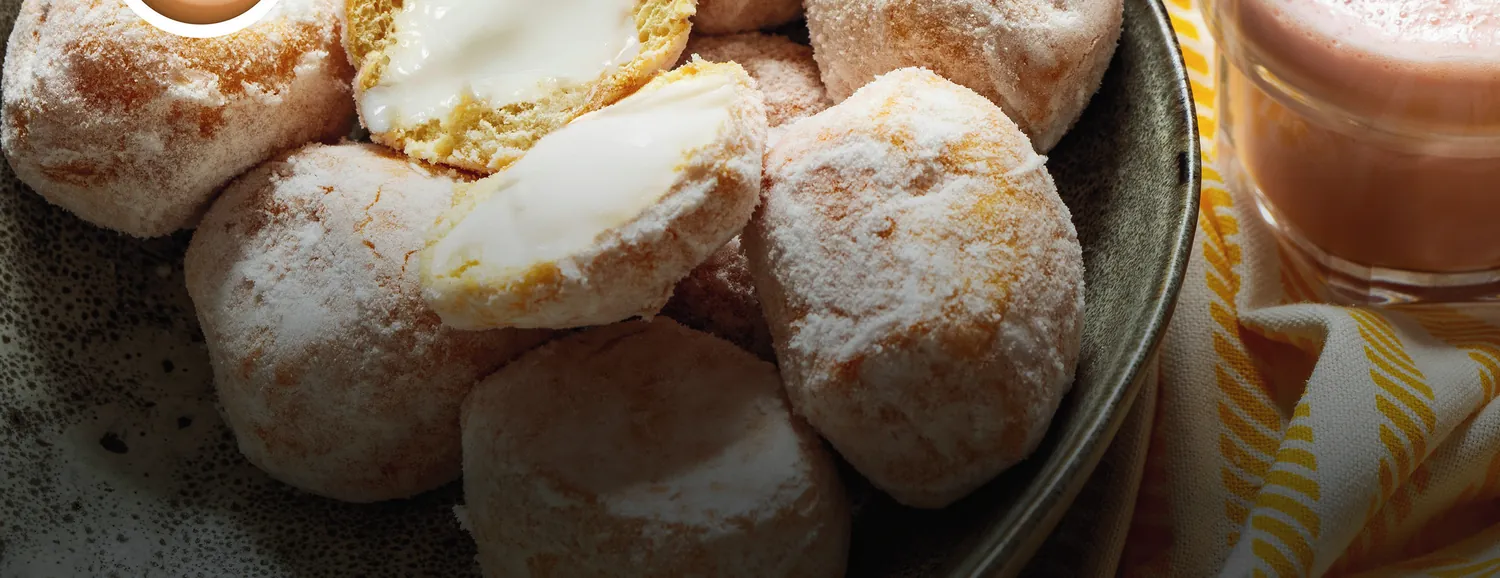 A bowl of Simply Doughnuts mini ring doughnuts beside a mug of coffee