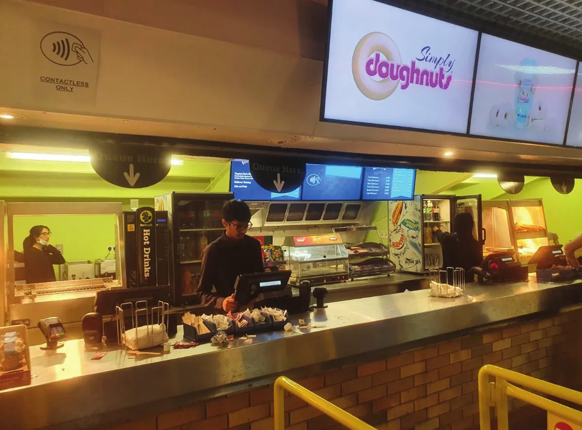 Simply Doughnuts on a hot food counter with menu screens above