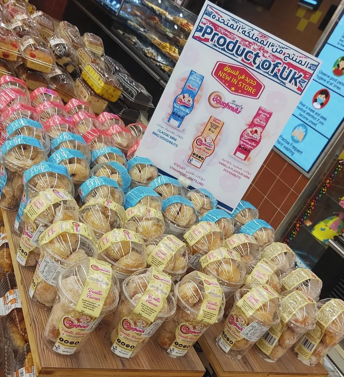 Simply Doughnuts packs stacked on a wooden retail display beside a Product of UK sign